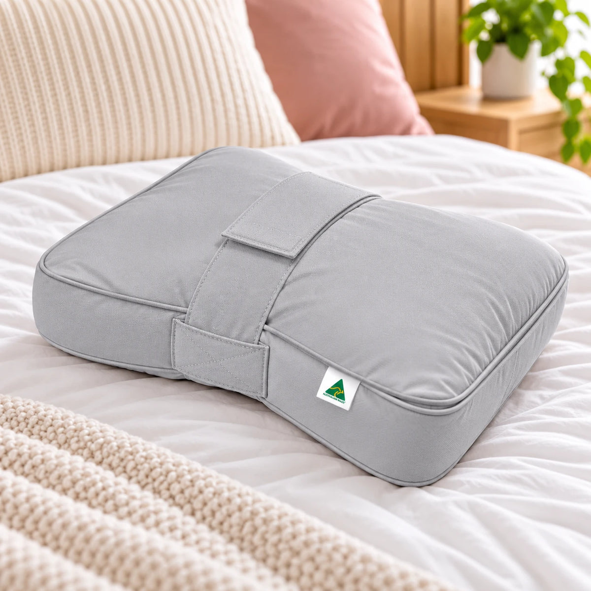 Grey Australian Made knee and leg pillow displayed on a bed