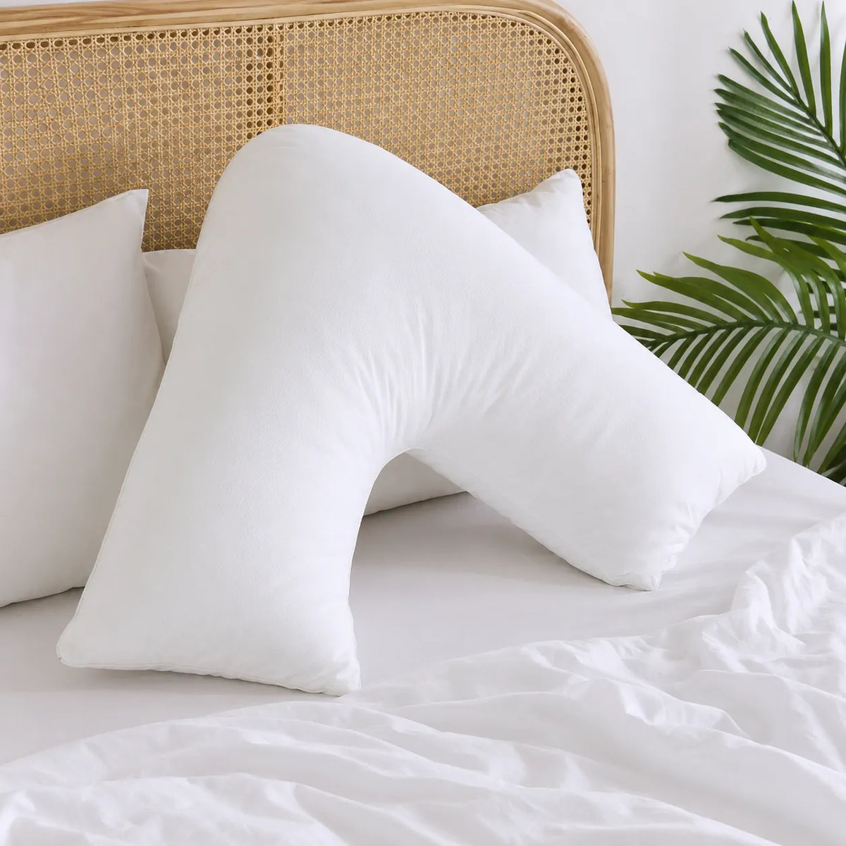 V shaped support pillow on a bed in a bright bedroom setting