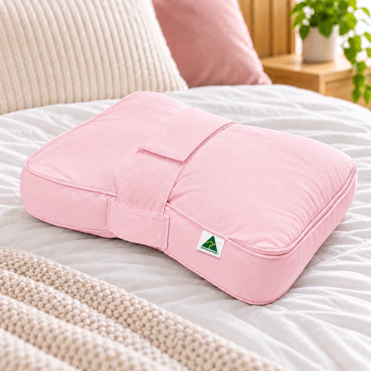 Pink Australian Made knee and leg pillow displayed on a bed