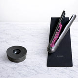 Hair straightener displayed upright on a white marble bench