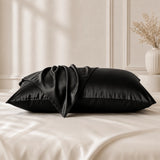 Black silk pillowcases displayed on a bed with mulberry silk pillowcases