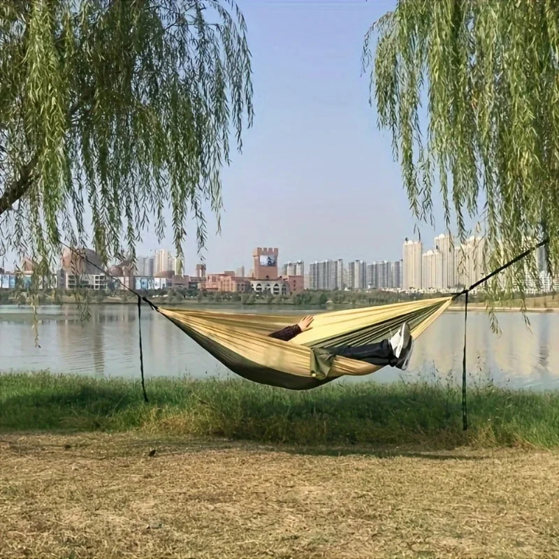 Lightweight camping hammock set up between trees by the lake