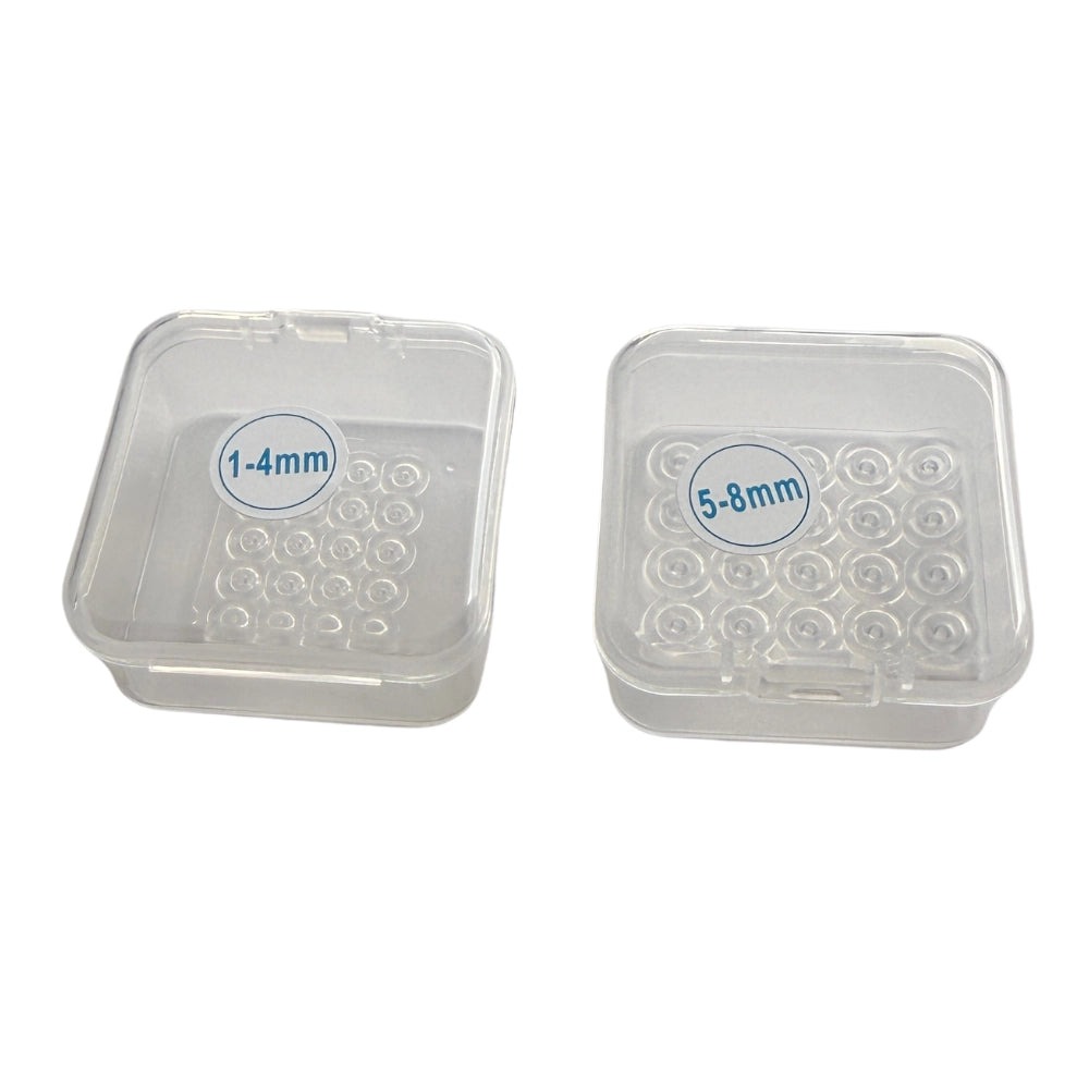 Two small refill trays containing elastic bands for skin tag removal device